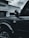 A black vehicle is parked in front of a building with signage that reads 'Dentistry.' The vehicle's side view mirror and part of the door are visible, along with the 'Outer Banks' emblem. The architecture of the building includes stone and brick elements.