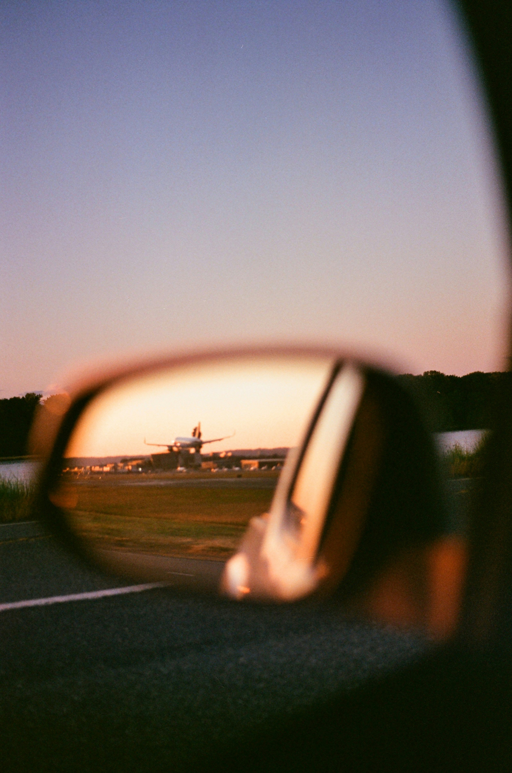 a rear view mirror reflecting an airplane on a runway