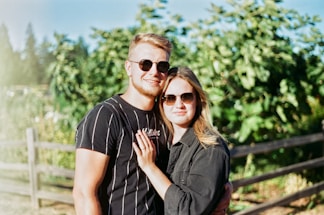 A friendly home inspector talking with a couple in front of a house on a sunny day.