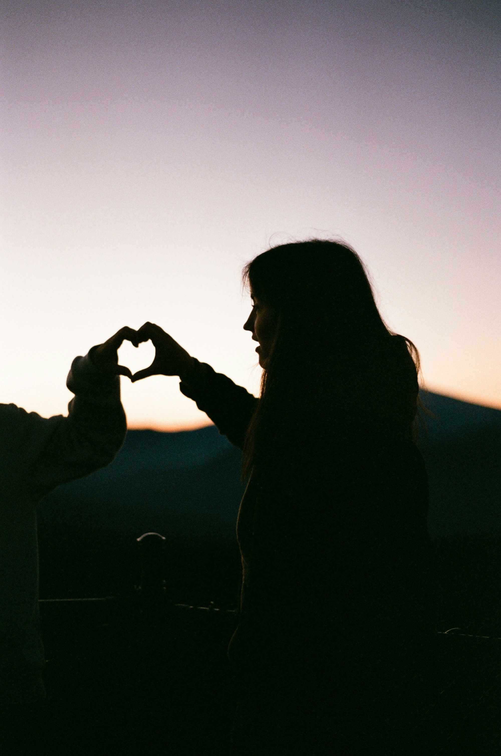 two people making a heart shape with their hands