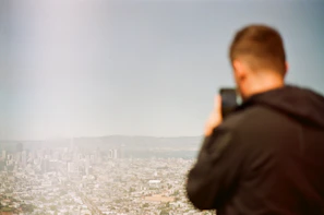 Lifestyle shot of a person using a smart gadget outdoors with a blurred cityscape behind.