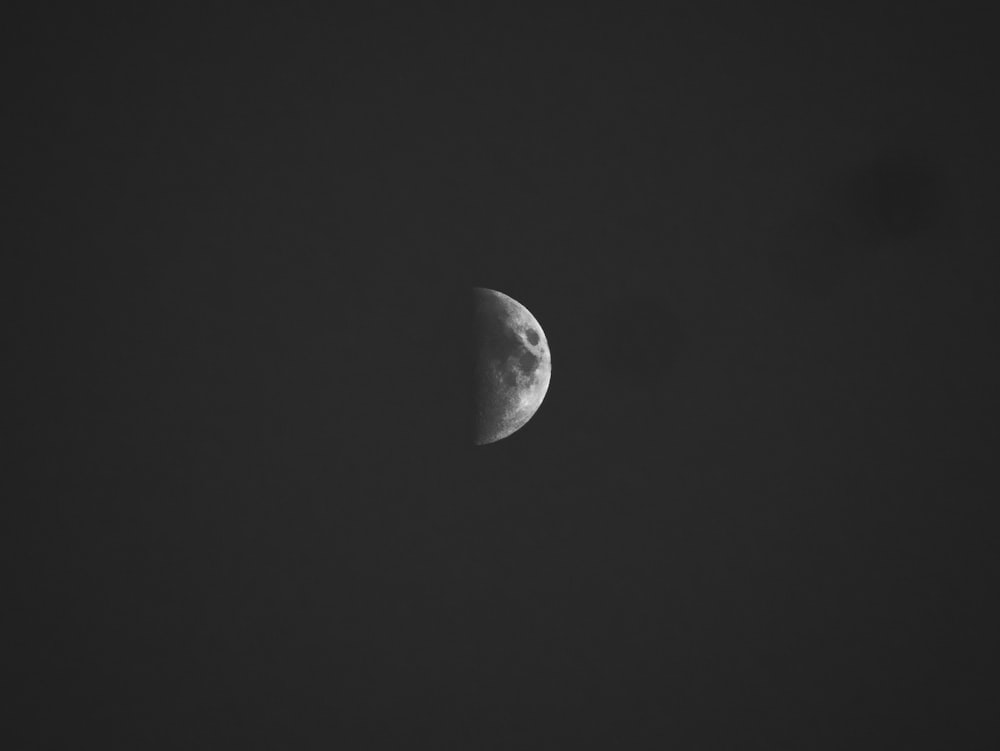 a half moon is seen in the dark sky