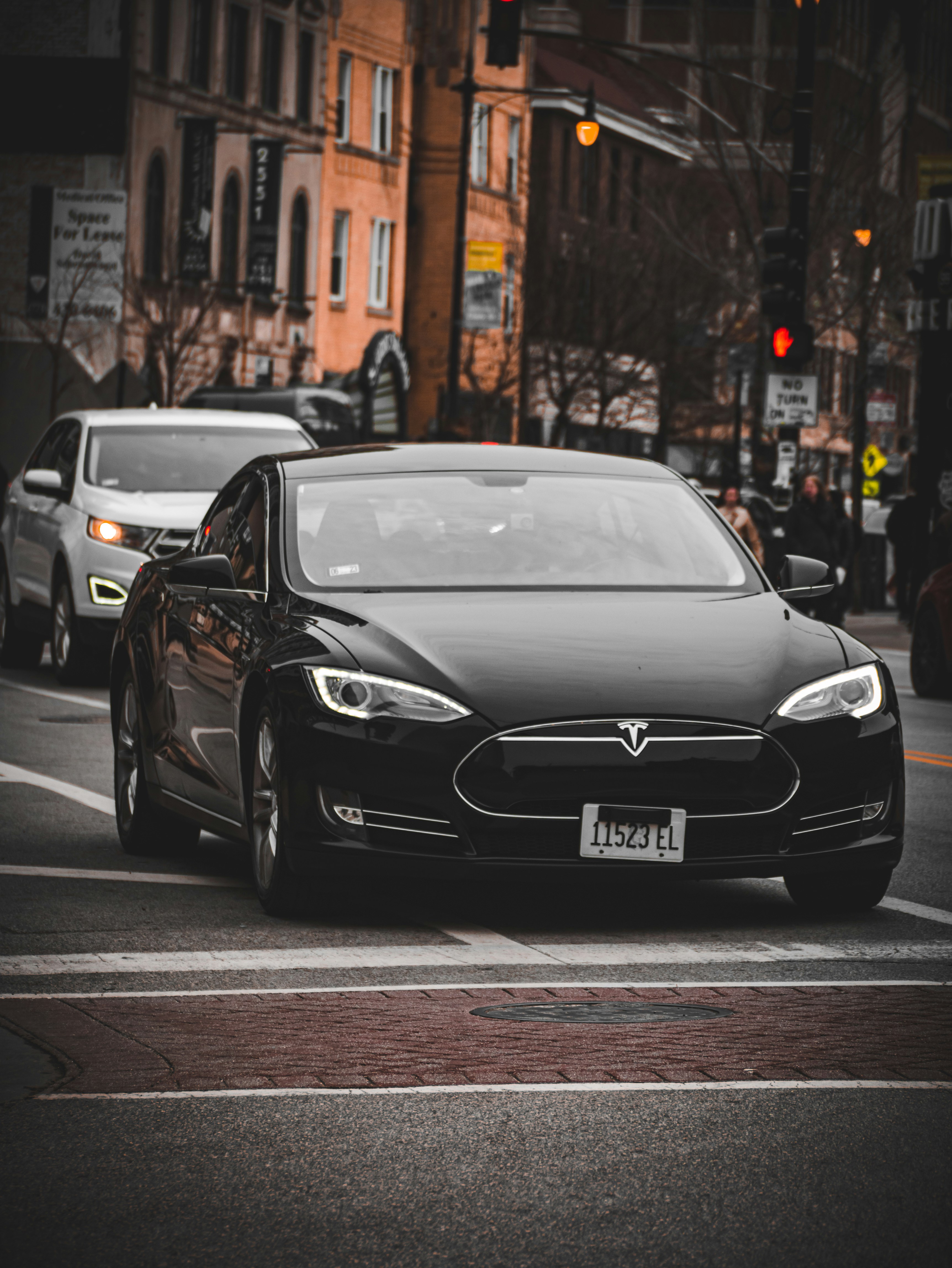 a black car driving down a street next to tall buildings