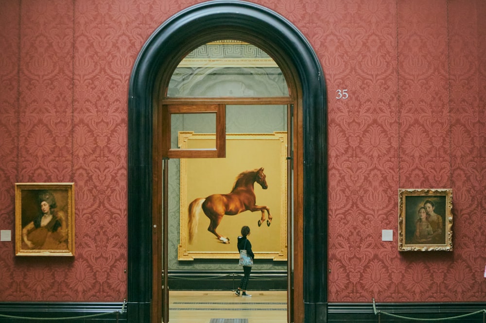 Un hombre parado frente a una pintura de un caballo