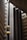An interior view of a modern building featuring a sleek, vertical elevator shaft with glass elevators and balconies. The architecture showcases geometric patterns with a mix of concrete and metal elements. Soft lighting adds a warm ambiance to the scene.