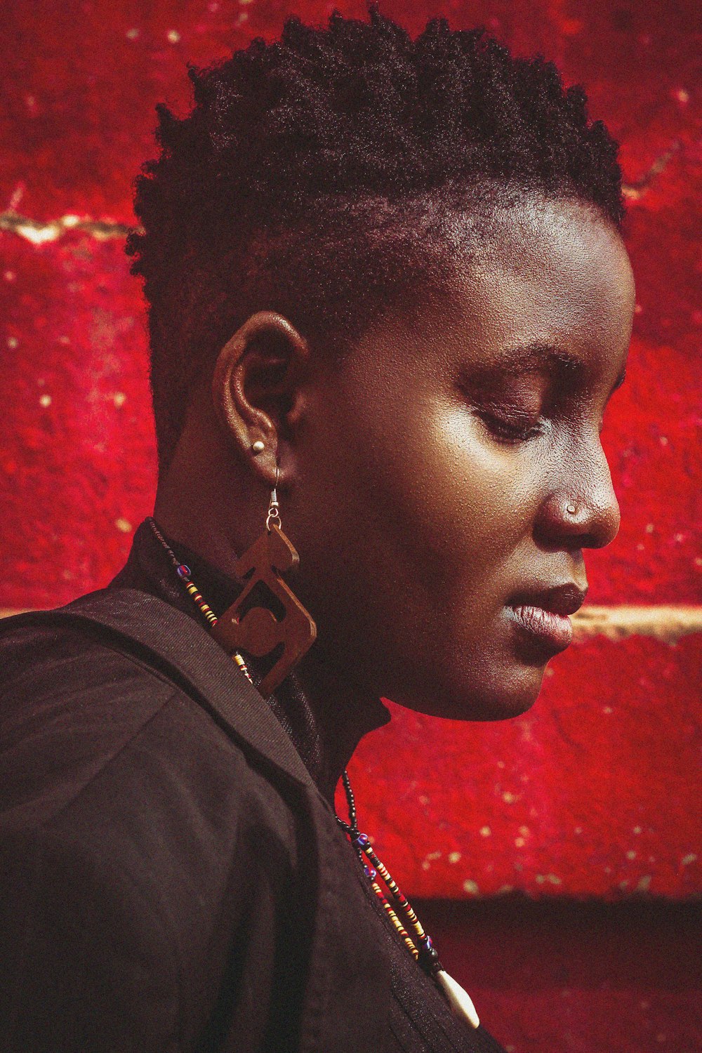 a woman with short hair standing in front of a red wall