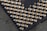 A close-up view of a grid of metallic pins protruding from a black surface, likely part of a computer processor. The pins are uniformly arranged and appear to be gold-plated, reflecting light in a bright contrast against the dark background.