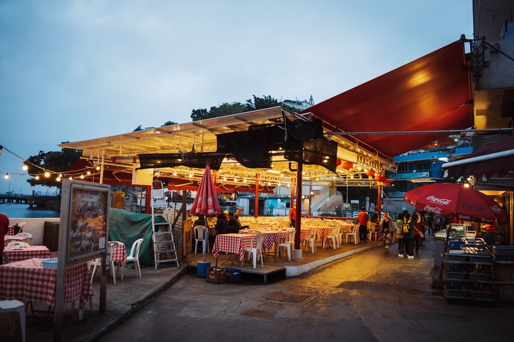 a group of people sitting at tables under umbrellas