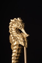 Luxurious black and gold shark sculpture illuminated softly against a dark background.