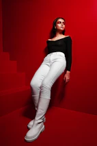 A model wearing a stylish black outfit standing against a vibrant, colorful background.
