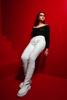 A model wearing a stylish black outfit standing against a vibrant, colorful background.
