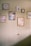 A wall adorned with several framed artworks, featuring abstract designs and illustrations of plants. The frames vary in size and color, and are neatly arranged, creating an aesthetically pleasing display.