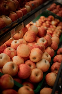 A bountiful display of red and yellow apples in a grocery store setting, with rows of fresh apples organized in trays.