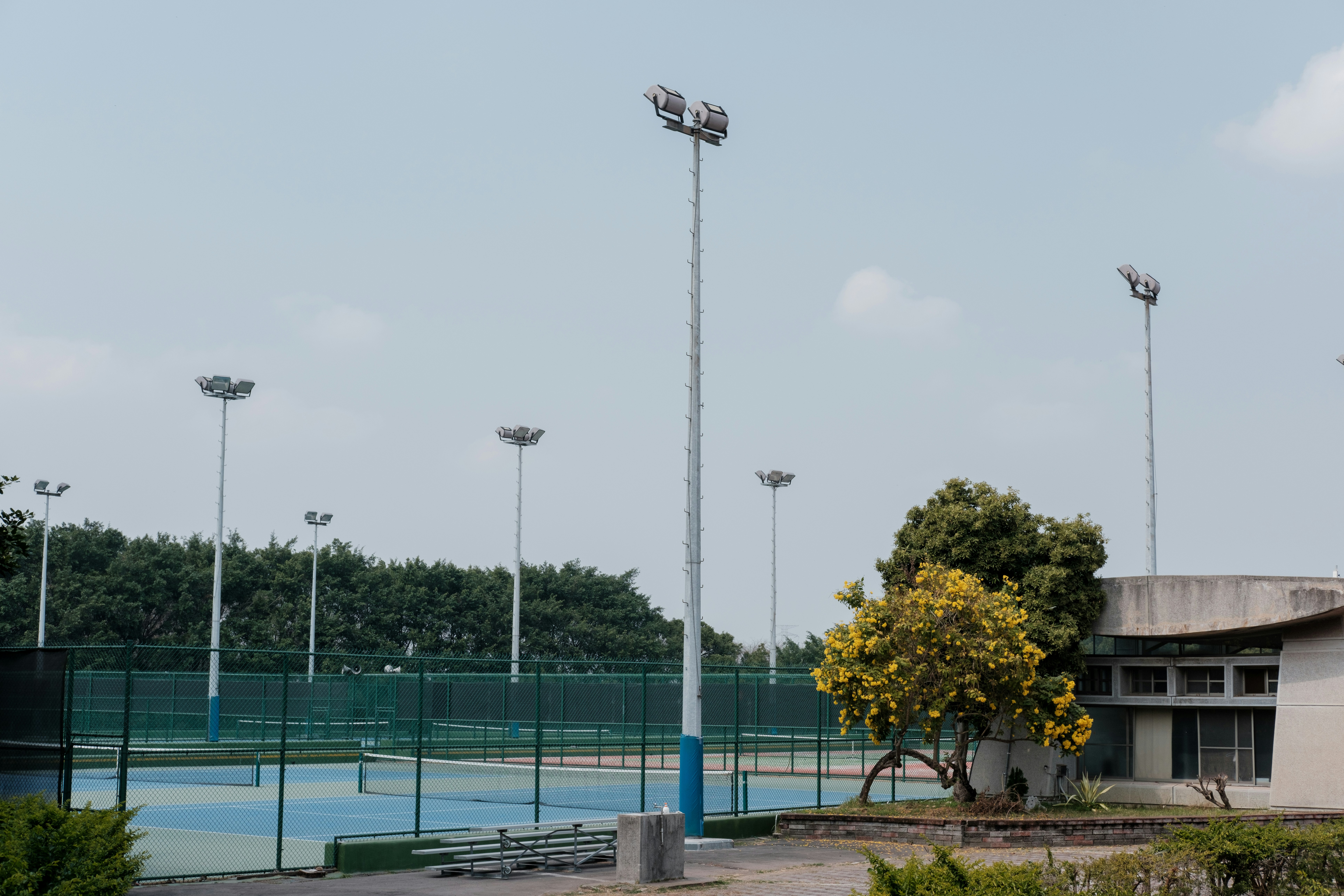 Vibrant green synthetic grass tennis court with modern floodlighting towers at dusk
