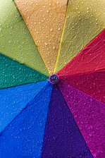 A vibrant photo of a Solumbre foldable umbrella open on a sunny day with raindrops falling around it.