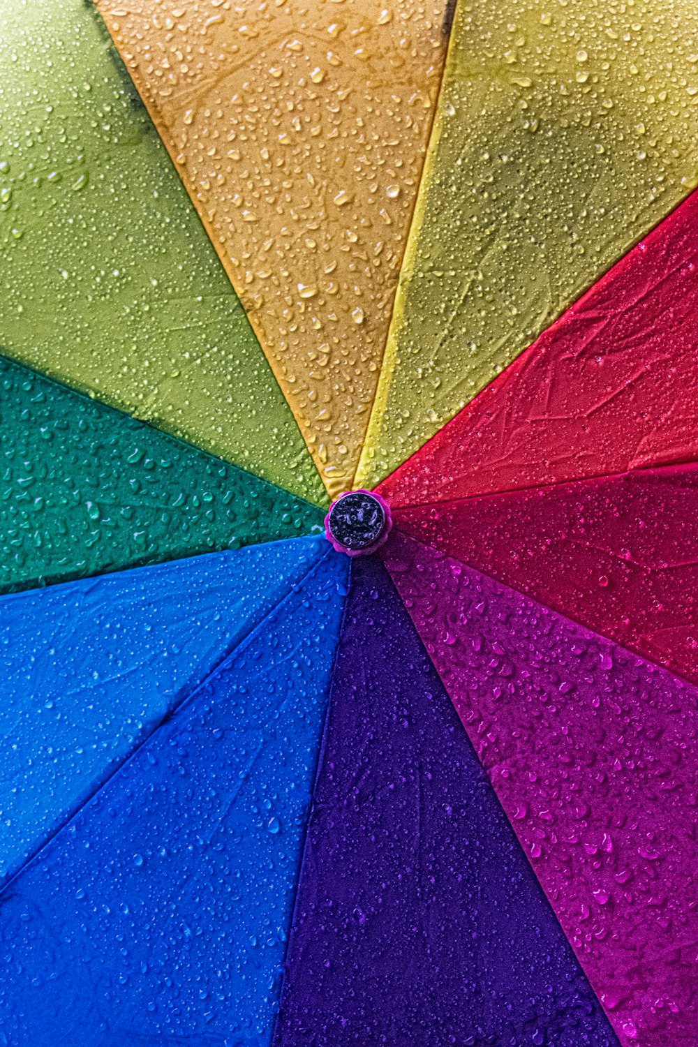 a multicolored umbrella with drops of water on it