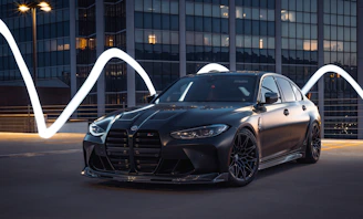 A sleek black luxury sedan parked in front of a modern Toronto skyline at dusk.