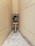 An old payphone is situated in a narrow, tiled hallway with beige walls. The phone booth is marked with 'World Call' branding and appears weathered, with visible wear on both the booth and the surrounding area.