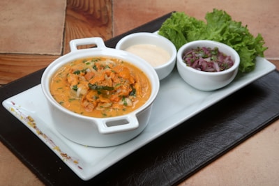 A steaming bowl of soup garnished with herbs on a simple white plate.