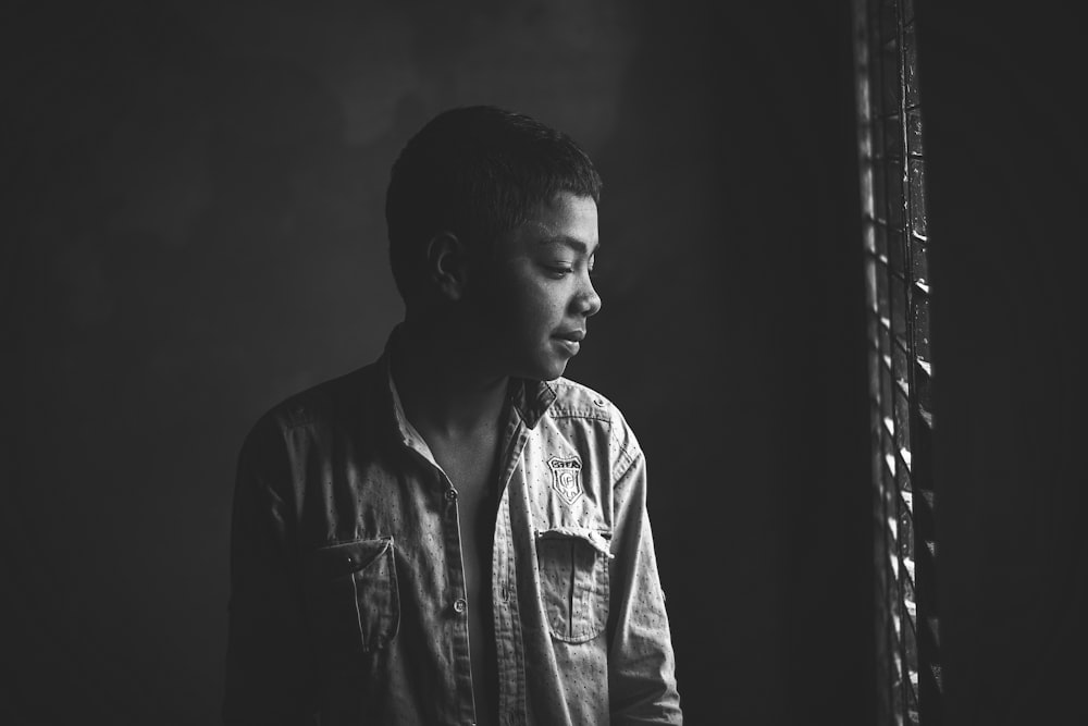 a black and white photo of a man looking out a window