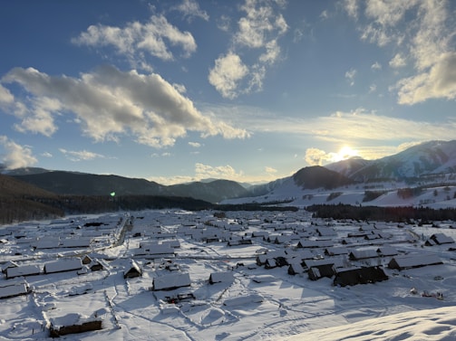 A peaceful mountain village blanketed in fresh snow under a clear blue sky.