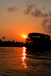 Sunset over Kerala's tranquil backwaters with traditional houseboats floating gently