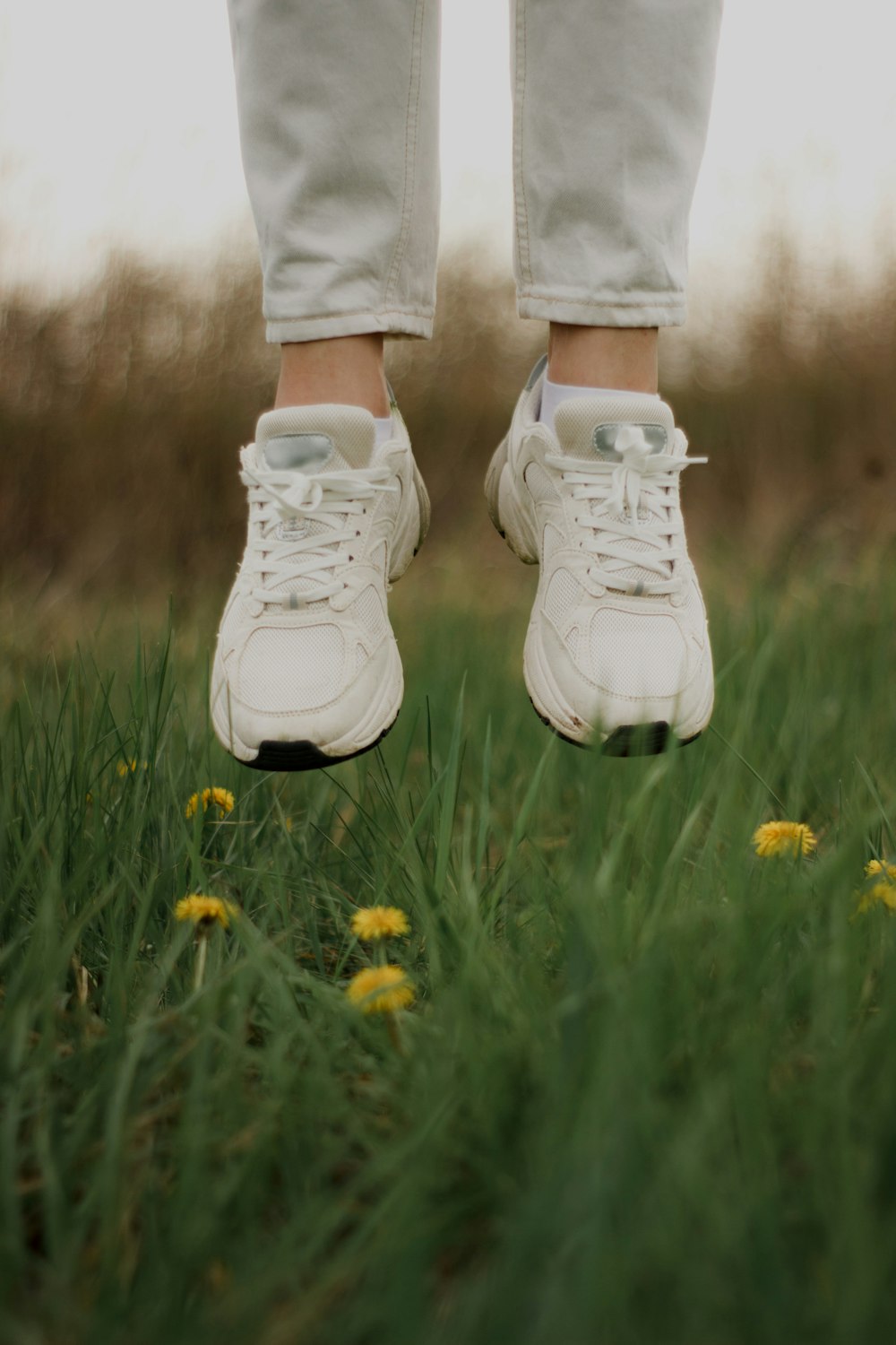 a person standing in a field with a pair of white shoes