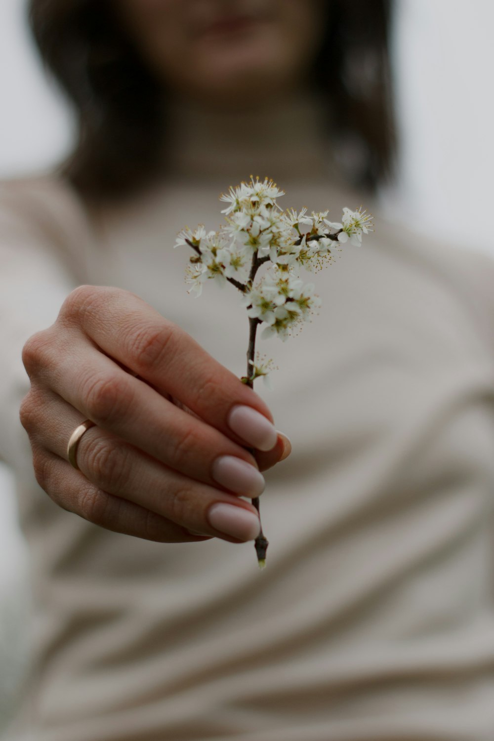 a woman holding a small white flower in her hand