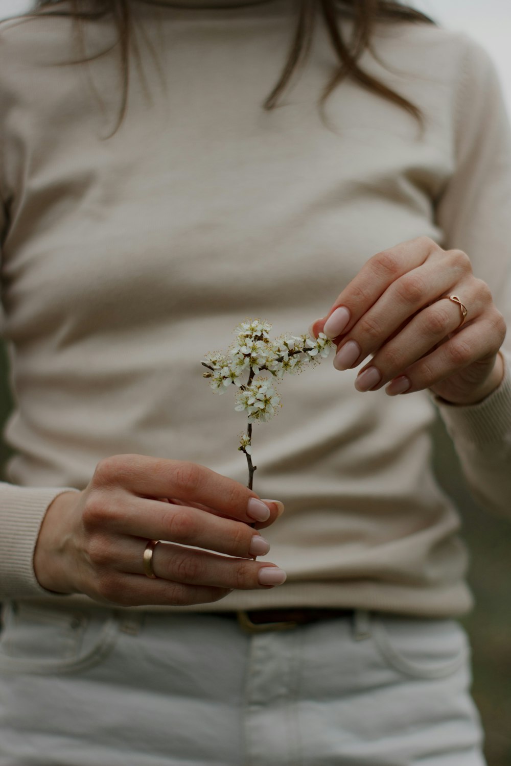 a woman holding a small white flower in her hands
