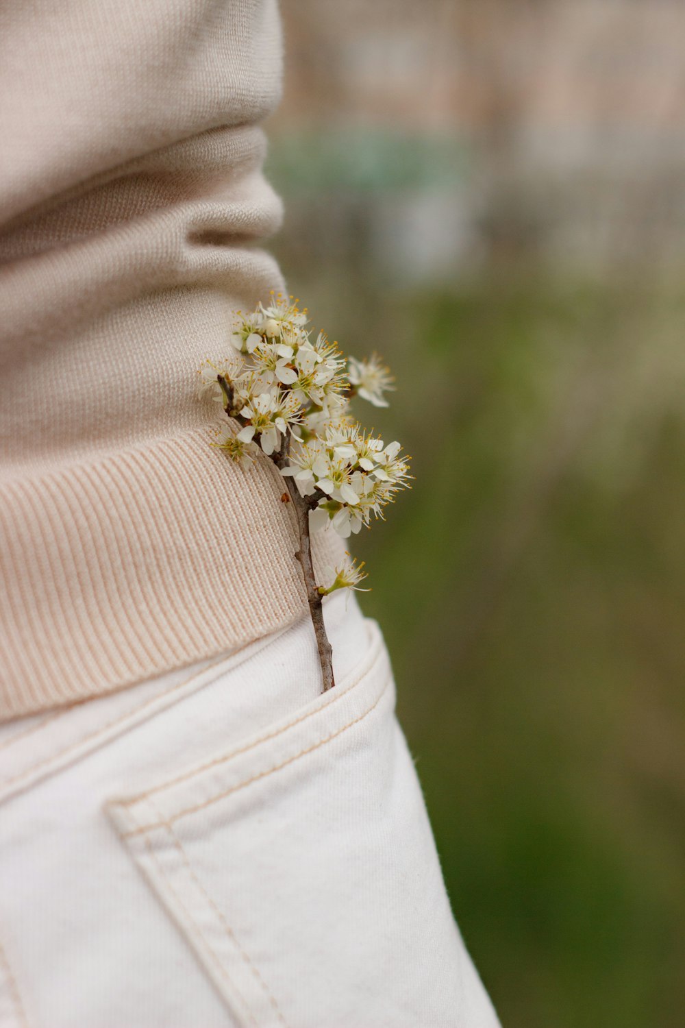 a small white flower sticking out of the pocket of someone's pants