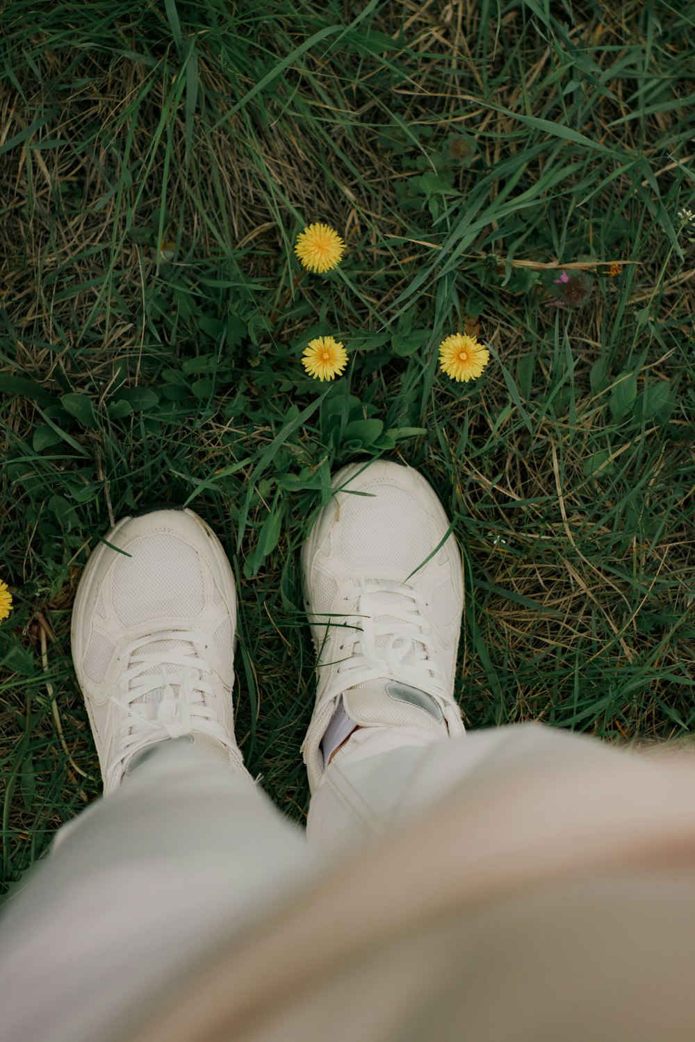 a person wearing white shoes standing in the grass