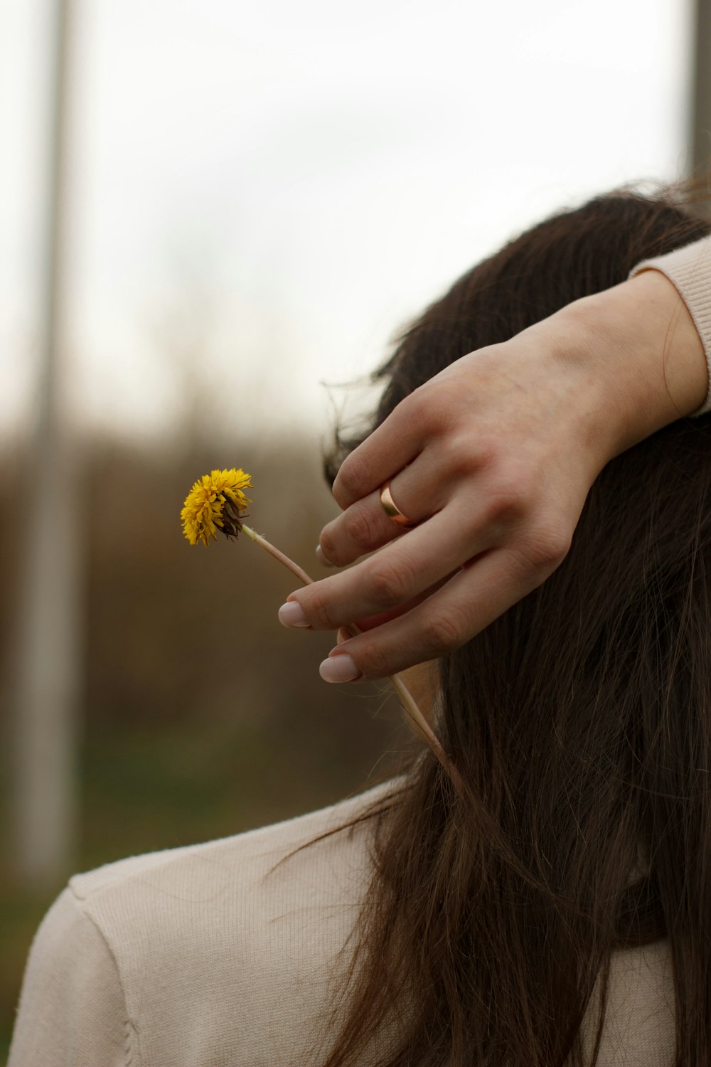 a woman holding a yellow flower in her hand