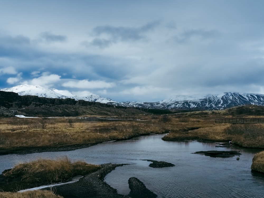 a river running through a dry grass covered field