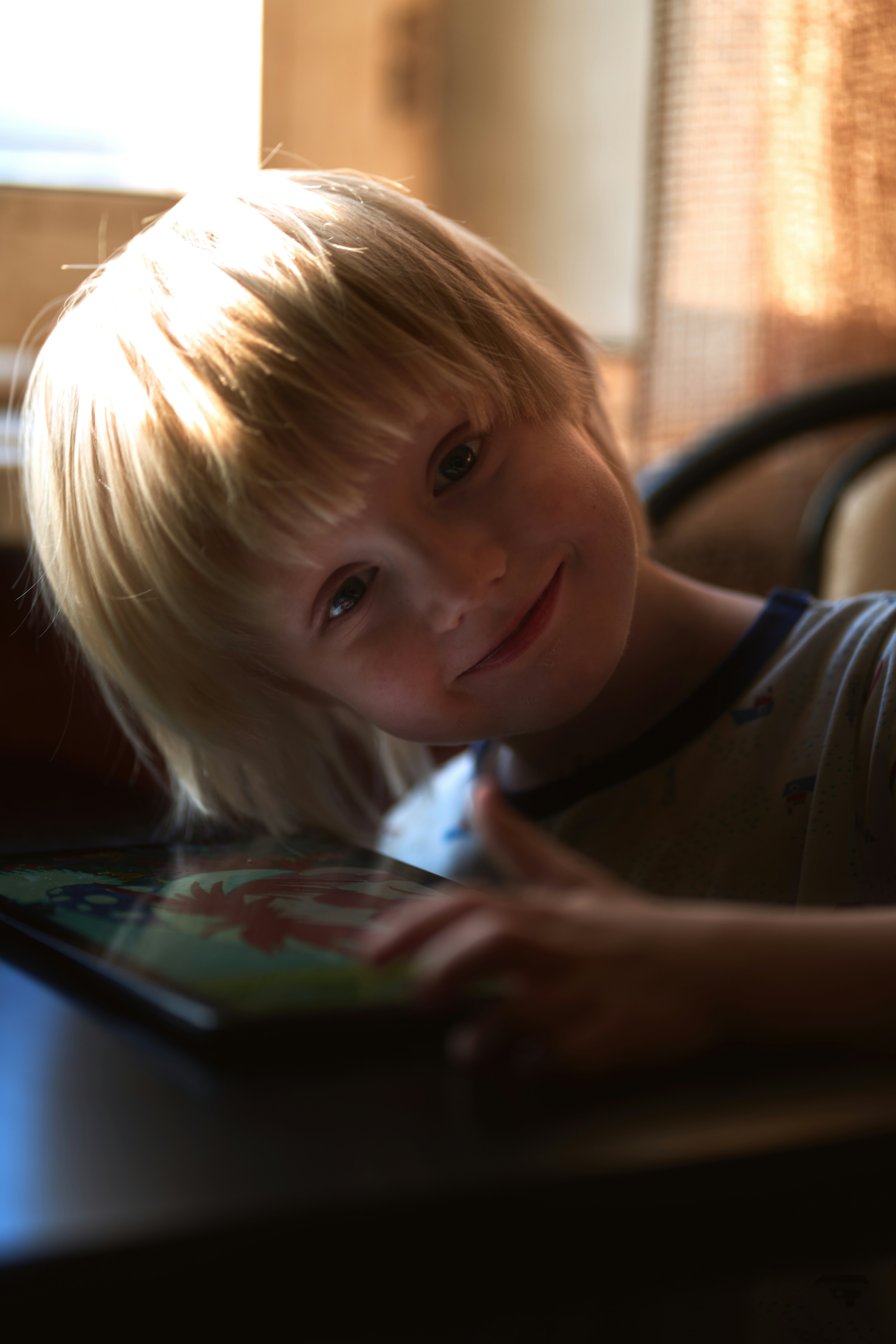 a young boy sitting at a table with a tablet