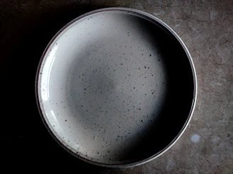 Close-up of a textured stoneware plate with a deep teal glaze and subtle speckled details.