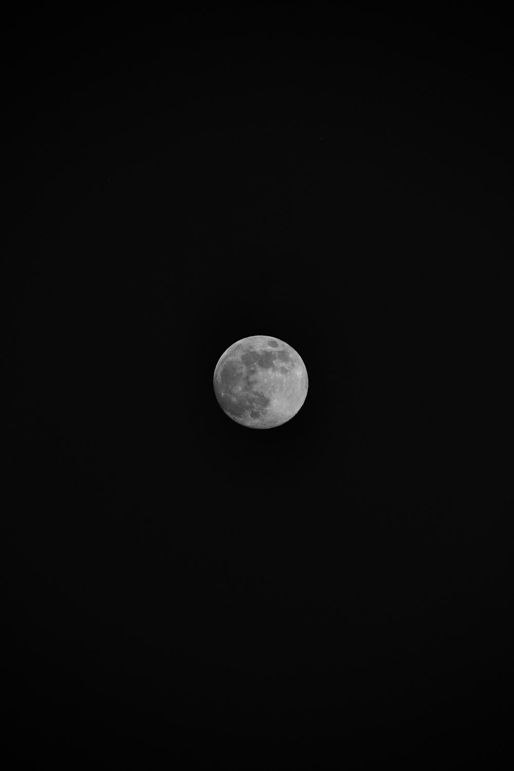 a full moon is seen in the dark sky