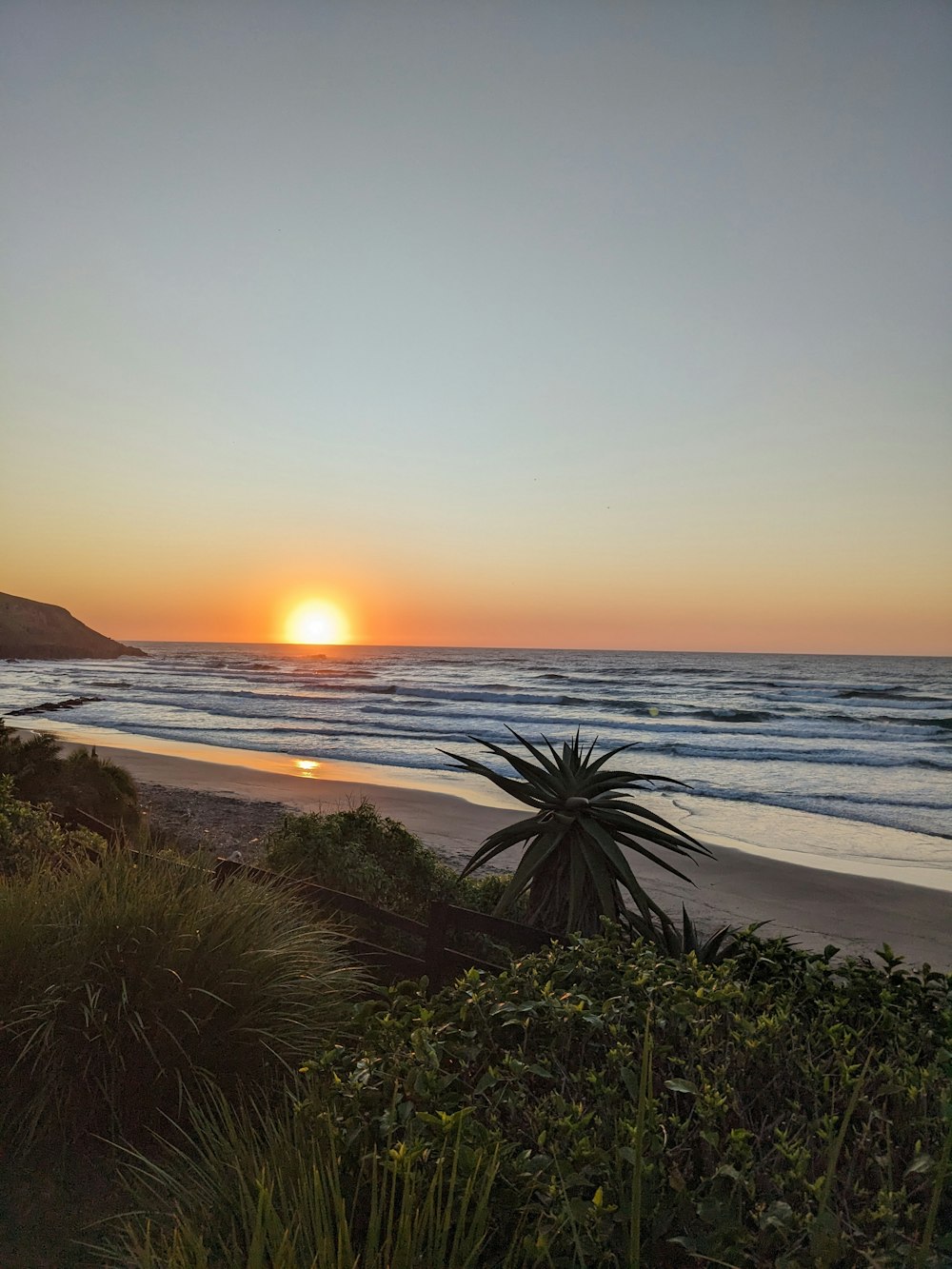 the sun is setting over the ocean on the beach