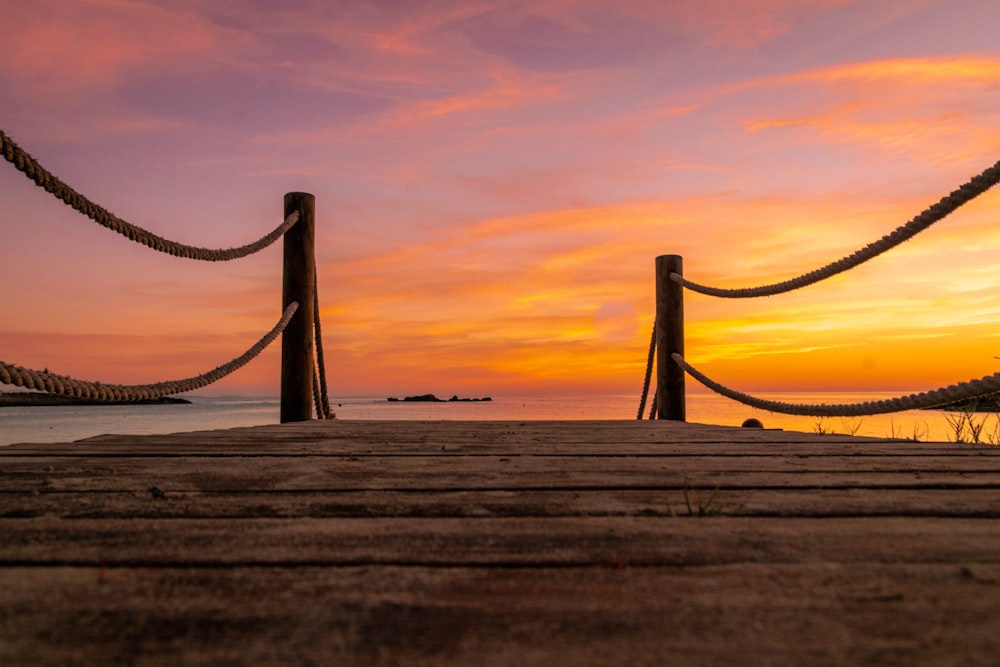 a wooden dock with a sunset in the background