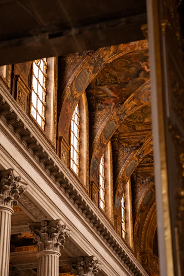 the ceiling of a building with columns and paintings on it