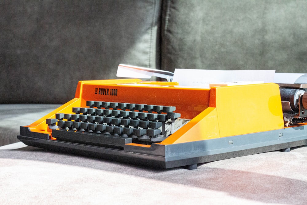 Una máquina de escribir de juguete sentada en una mesa junto a un sofá