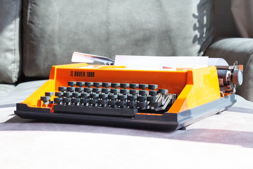 an orange and black typewriter sitting on a table