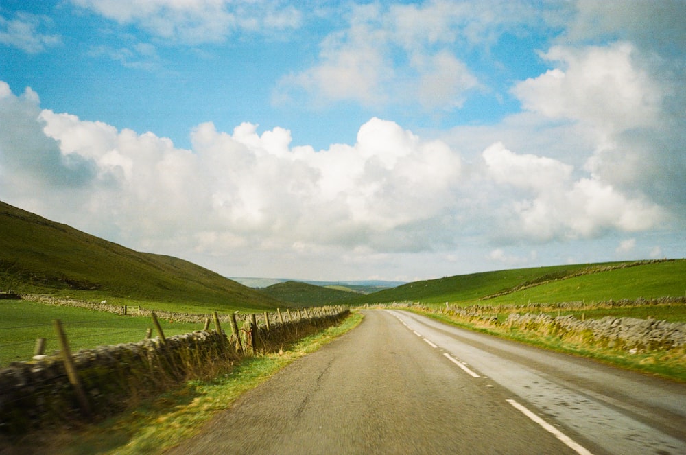 a car driving down a road next to a lush green hillside