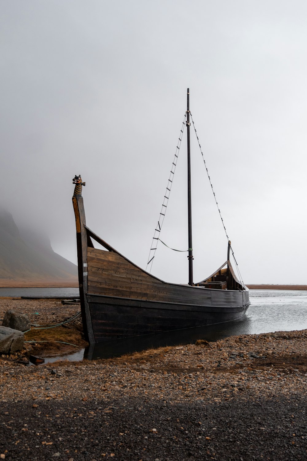 a boat sitting on top of a beach next to a body of water