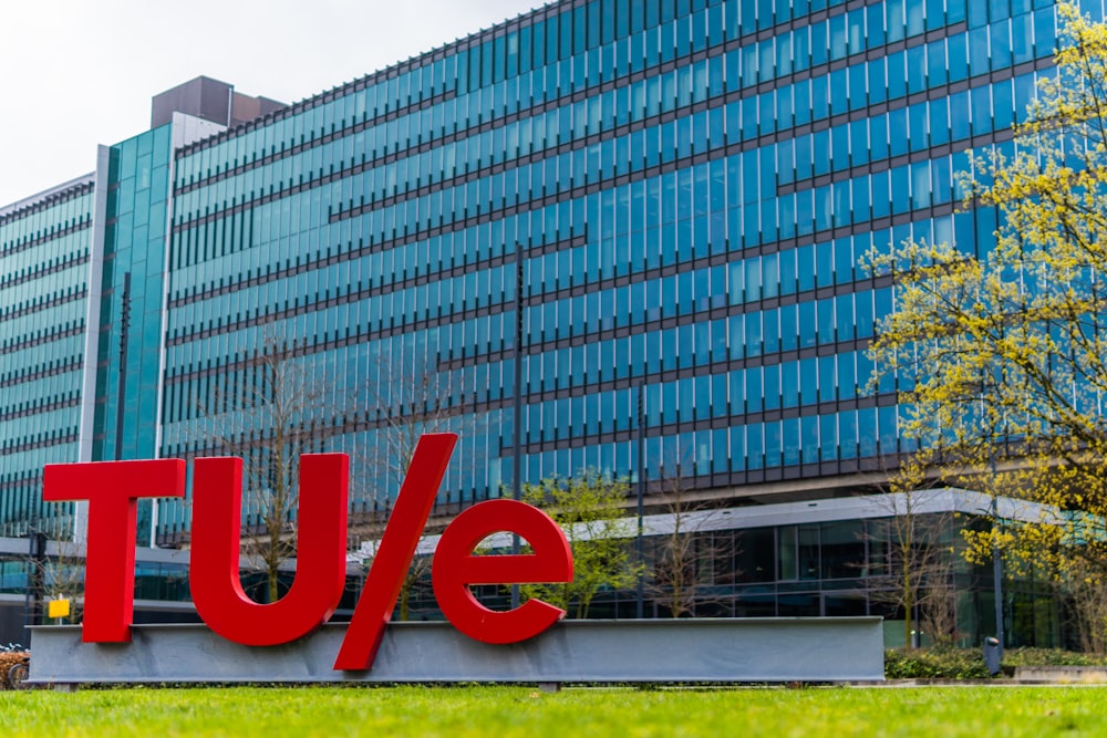 a large red sign sitting in front of a tall building