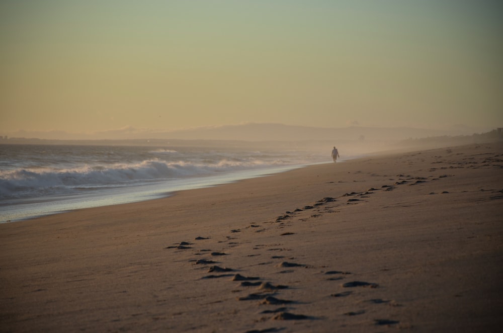 eine Person, die an einem Strand neben dem Meer spazieren geht