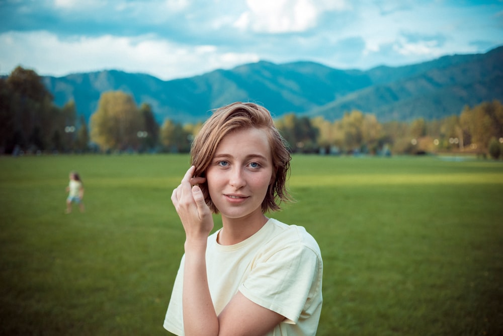 a girl in a field with mountains in the background