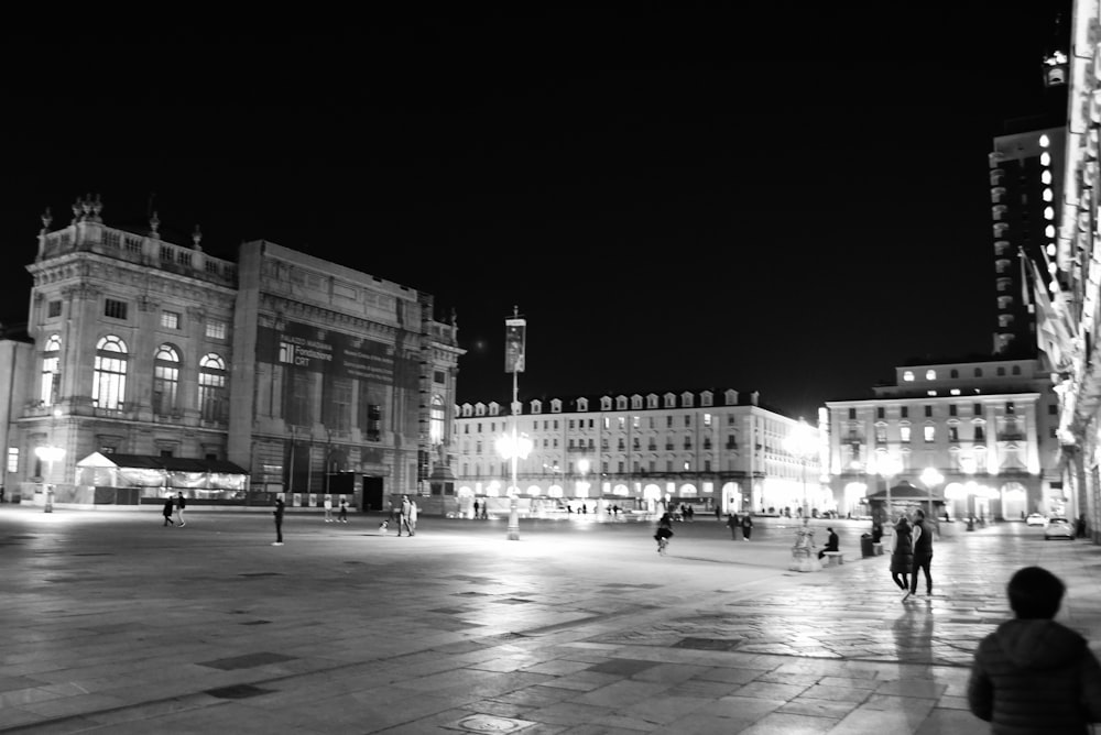 a black and white photo of a city square at night