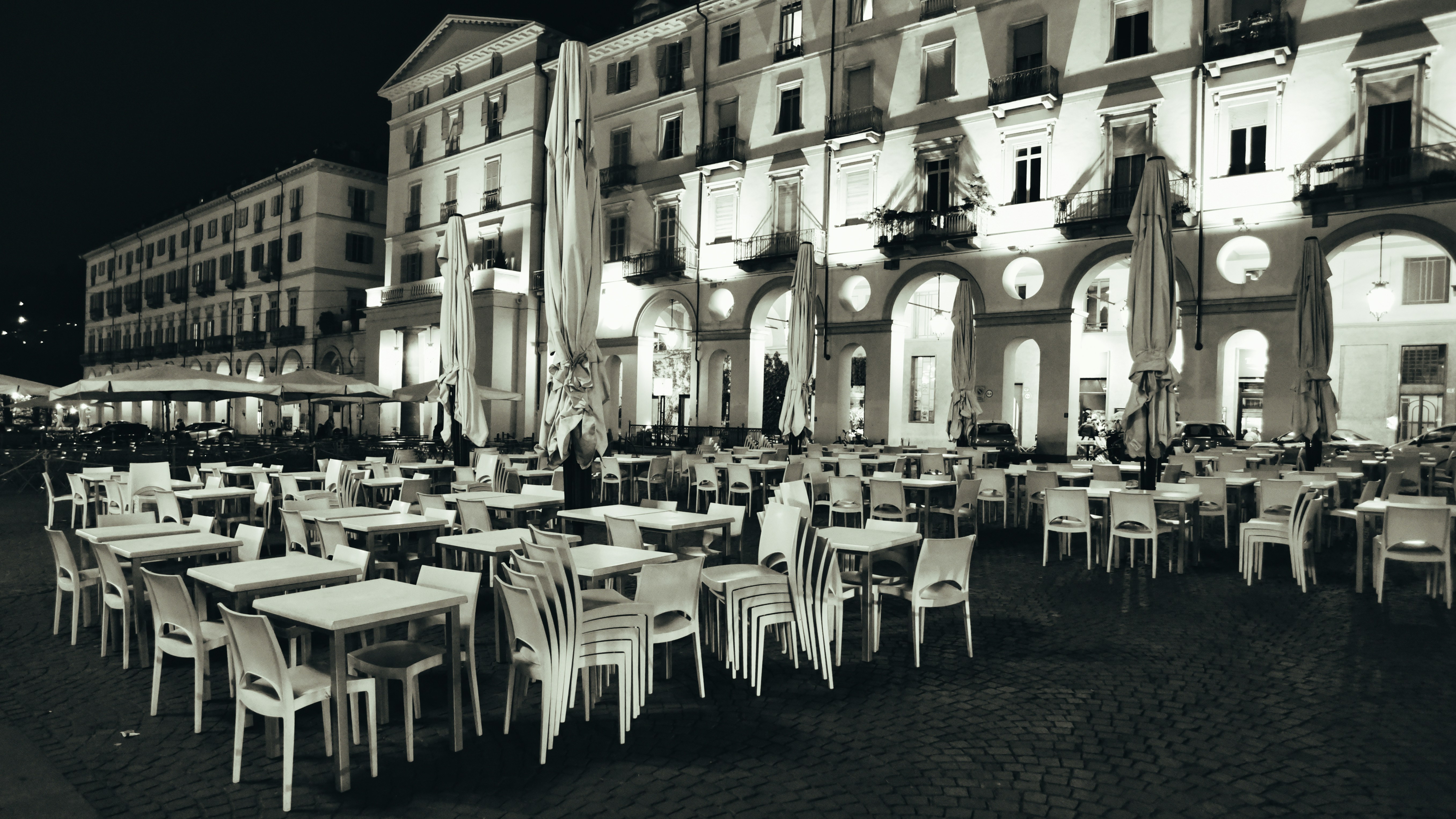 a black and white photo of tables and chairs in front of a building