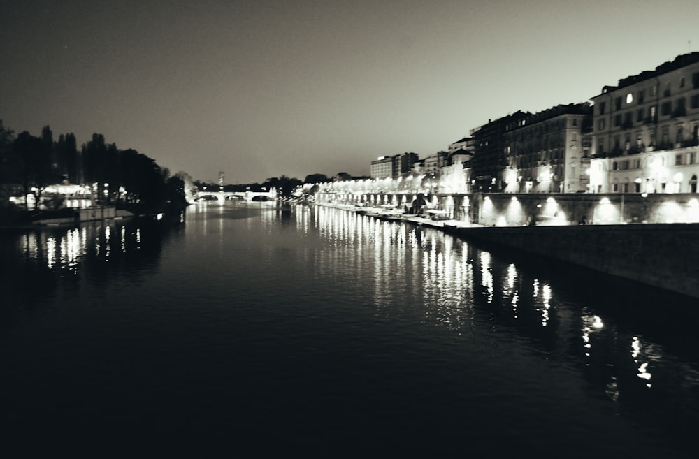 a black and white photo of a river at night