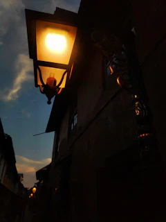 A moody shot of a deserted city alley at night, illuminated by a single flickering streetlamp.